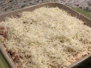 Fully assembled chicken spaghetti in casserole dish and topped with mozzarella and parmesan cheeses.